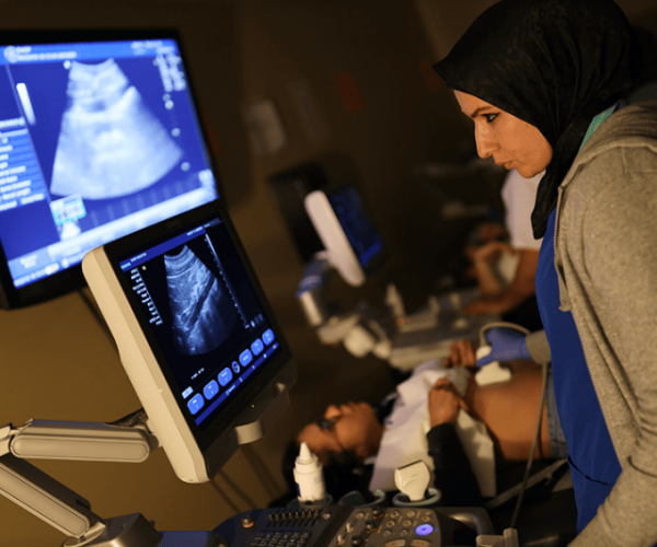 Woman Performing Diagnostic Ultrasound on Patient